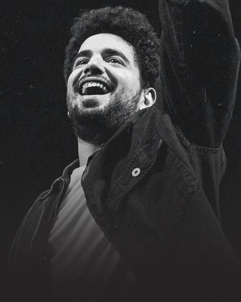 Samay Raina smiling in a black and white live performance portrait