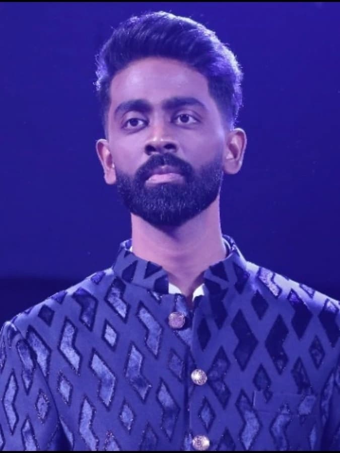 Pranit More in a blue patterned formal jacket under blue stage lighting